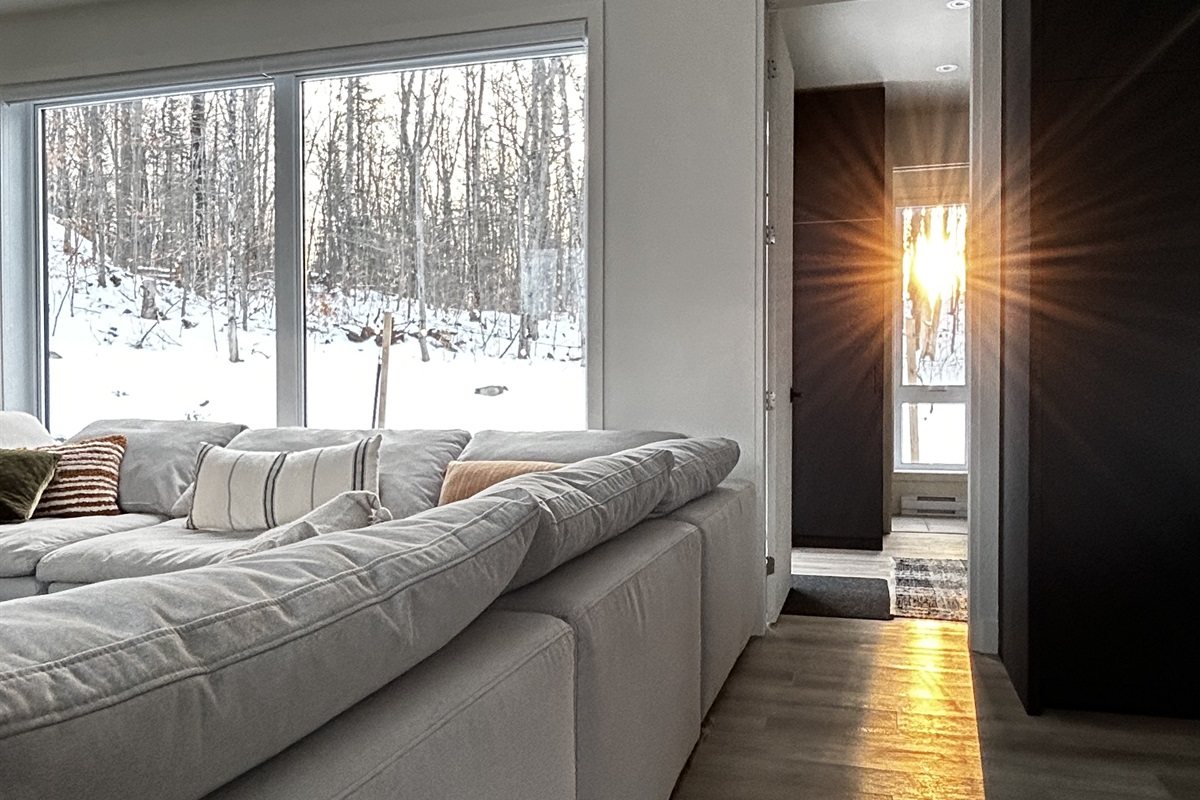 Le soleil bas de l’hiver sur le canapé, la neige lumineuse dehors