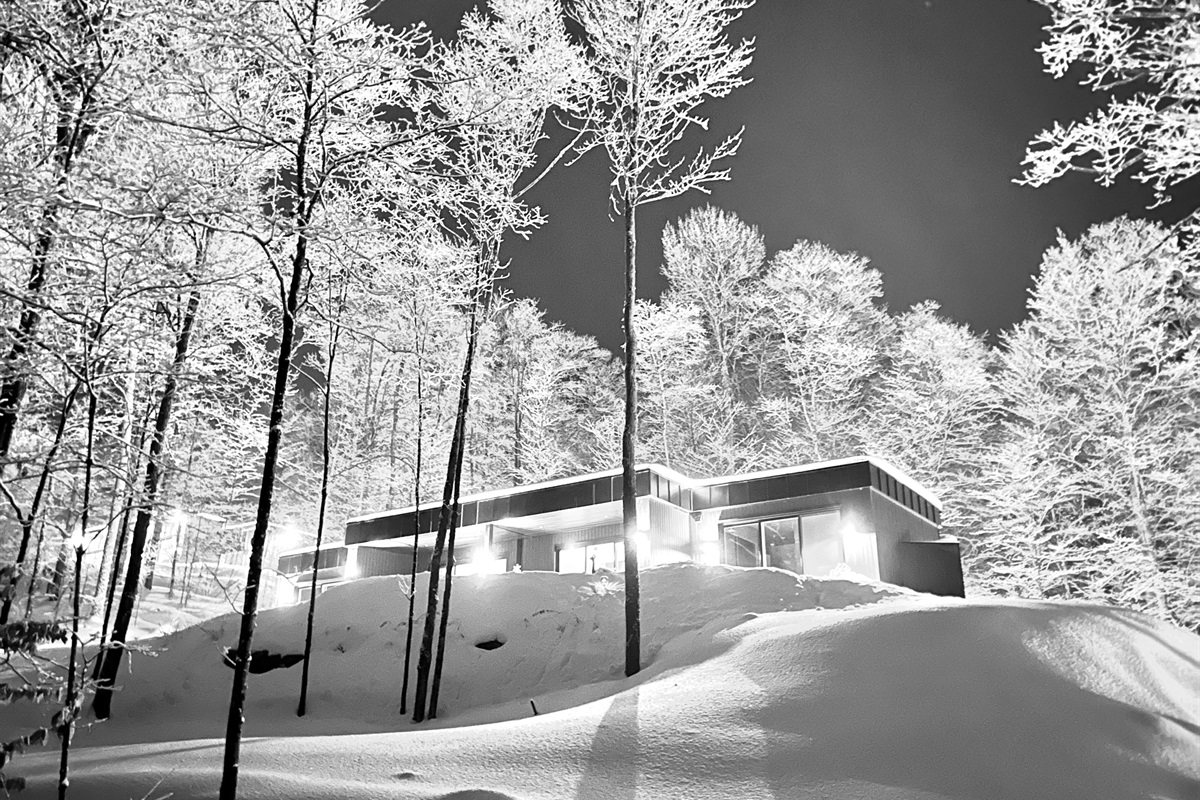 Le chalet la nuit sous les arbres givrés, en noir et blanc
